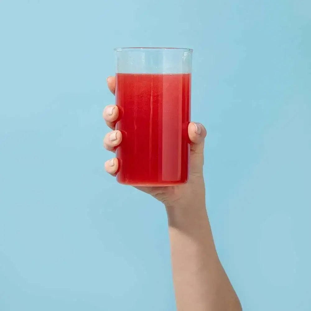 woman holding a glass of water with 1MD Nutrition CardioFitMD mixed in it